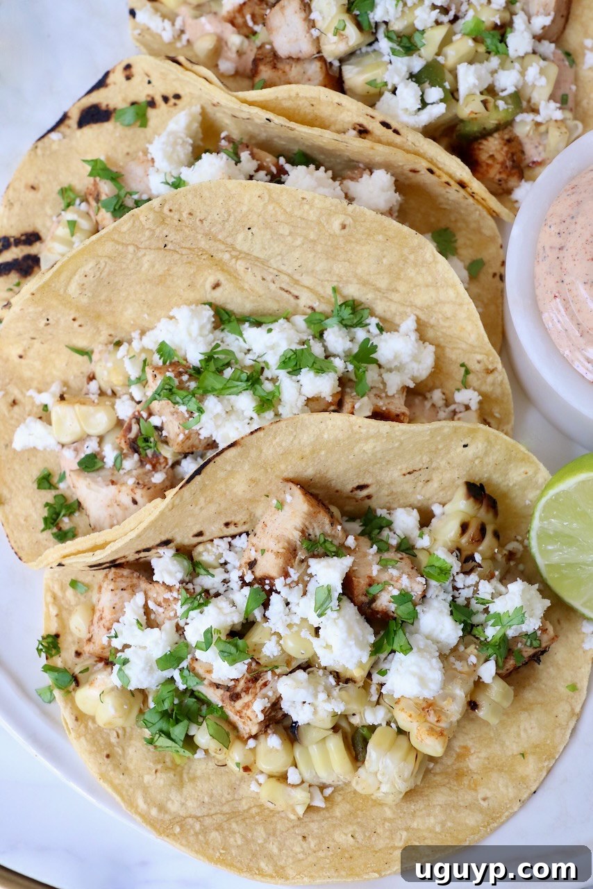 street corn and chicken tacos on plate with lime wedge