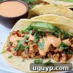 crumbled tofu taco topped with cilantro, avocado and chipotle sauce on a plate