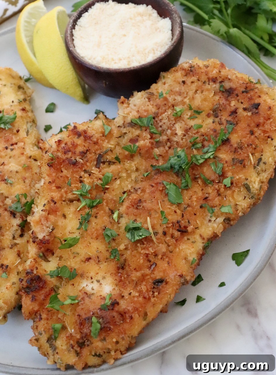 Crispy Parmesan Crusted Chicken on a plate with fresh lemon wedges, ready to be served.
