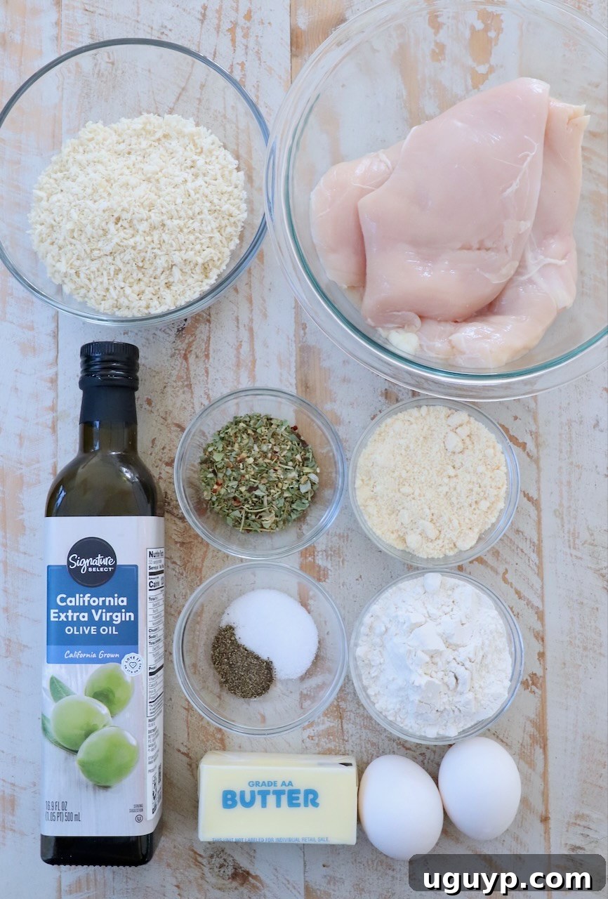 Ingredients for Parmesan Crusted Chicken laid out on a white wooden board.