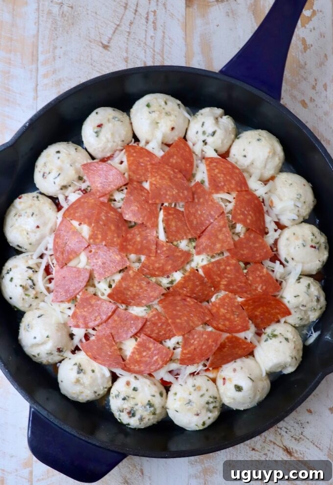 pepperoni pizza dip in the middle of a skillet surrounded by balls of dough