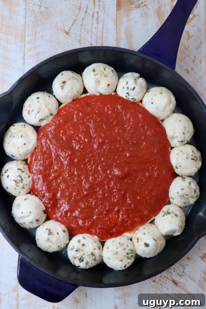 marinara sauce in the middle of a skillet surrounded by balls of dough