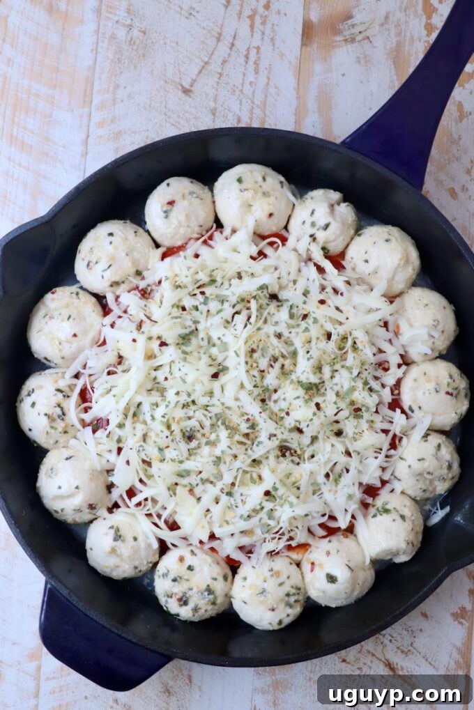 pizza dip in the middle of a skillet surrounded by balls of dough