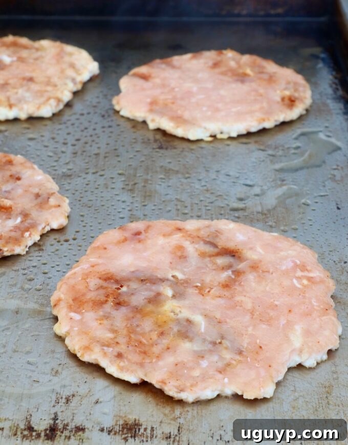 multiple smashed chicken burger patties sizzling on a griddle