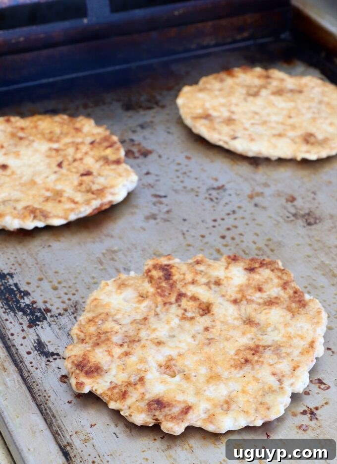 perfectly cooked, crispy smashed chicken patties resting on a griddle
