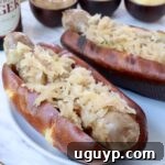 grilled bratwurst in a bun topped with sauerkraut on a plate