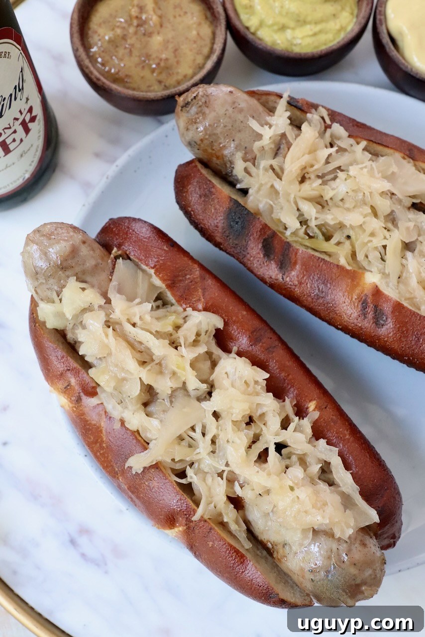 grilled bratwurst in pretzel bun topped with sauerkraut on a plate