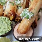 Crispy taquito dipped into a small bowl of chili lime sauce