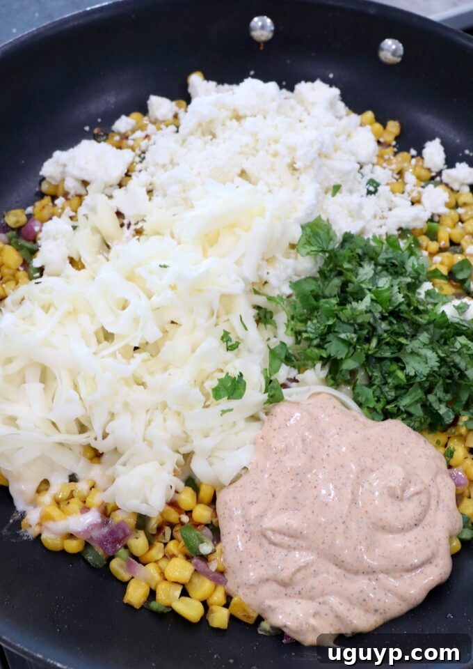 Skillet filled with charred corn, onions, and jalapeños, now combined with chili lime dressing, cilantro, and cheeses