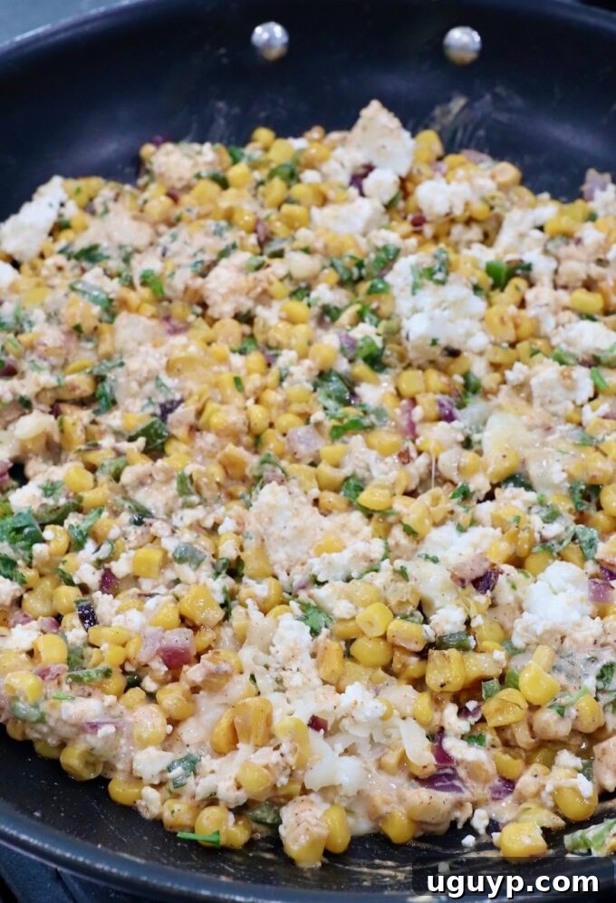 Creamy corn mixture blended with cheeses, fresh cilantro, and chili lime sauce in a skillet, creating a flavorful filling