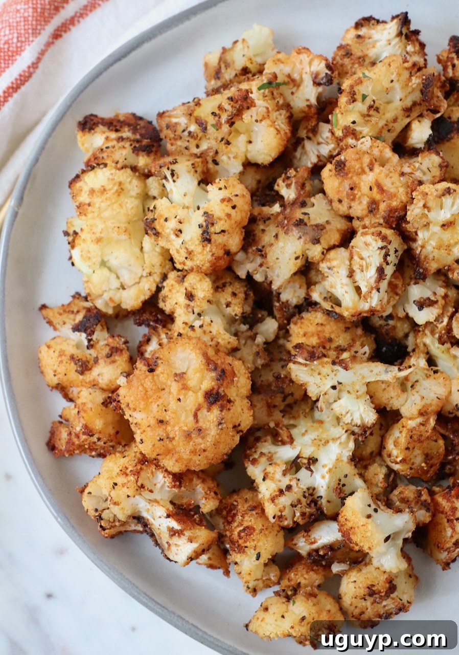 A plate of perfectly roasted, seasoned cauliflower florets, ready to be served.