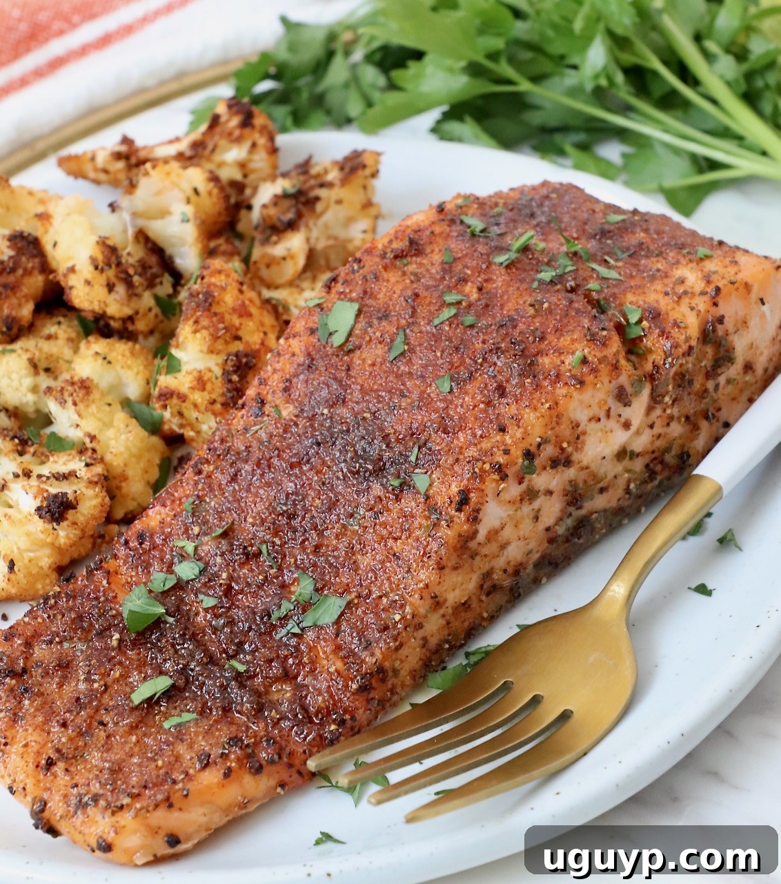 cooked salmon filet on plate with fork and roasted cauliflower
