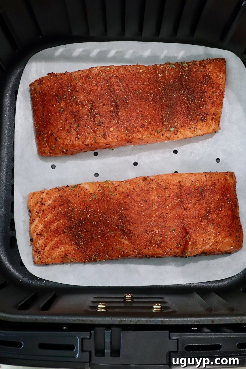seasoned salmon filets in an air fryer basket