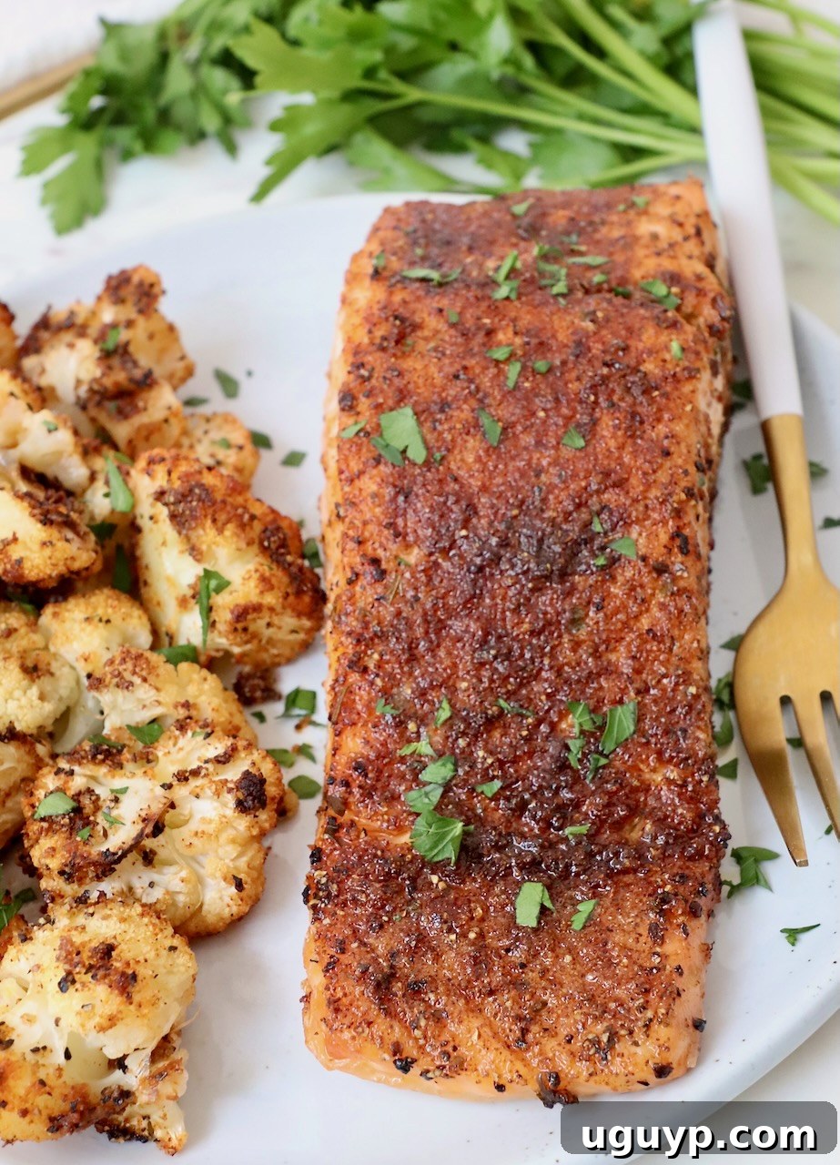 cooked, seasoned salmon on a plate with roasted cauliflower and a fork