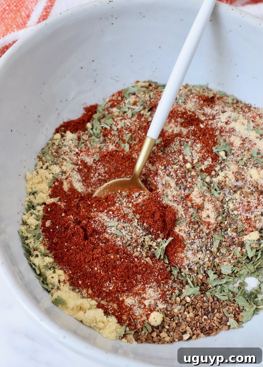 A close-up shot of freshly mixed salmon seasoning in a white bowl with a wooden spoon, showcasing its rich color and texture.