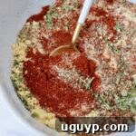 Herbs and spices mixed together in a bowl with a spoon, showing the finished salmon seasoning blend.
