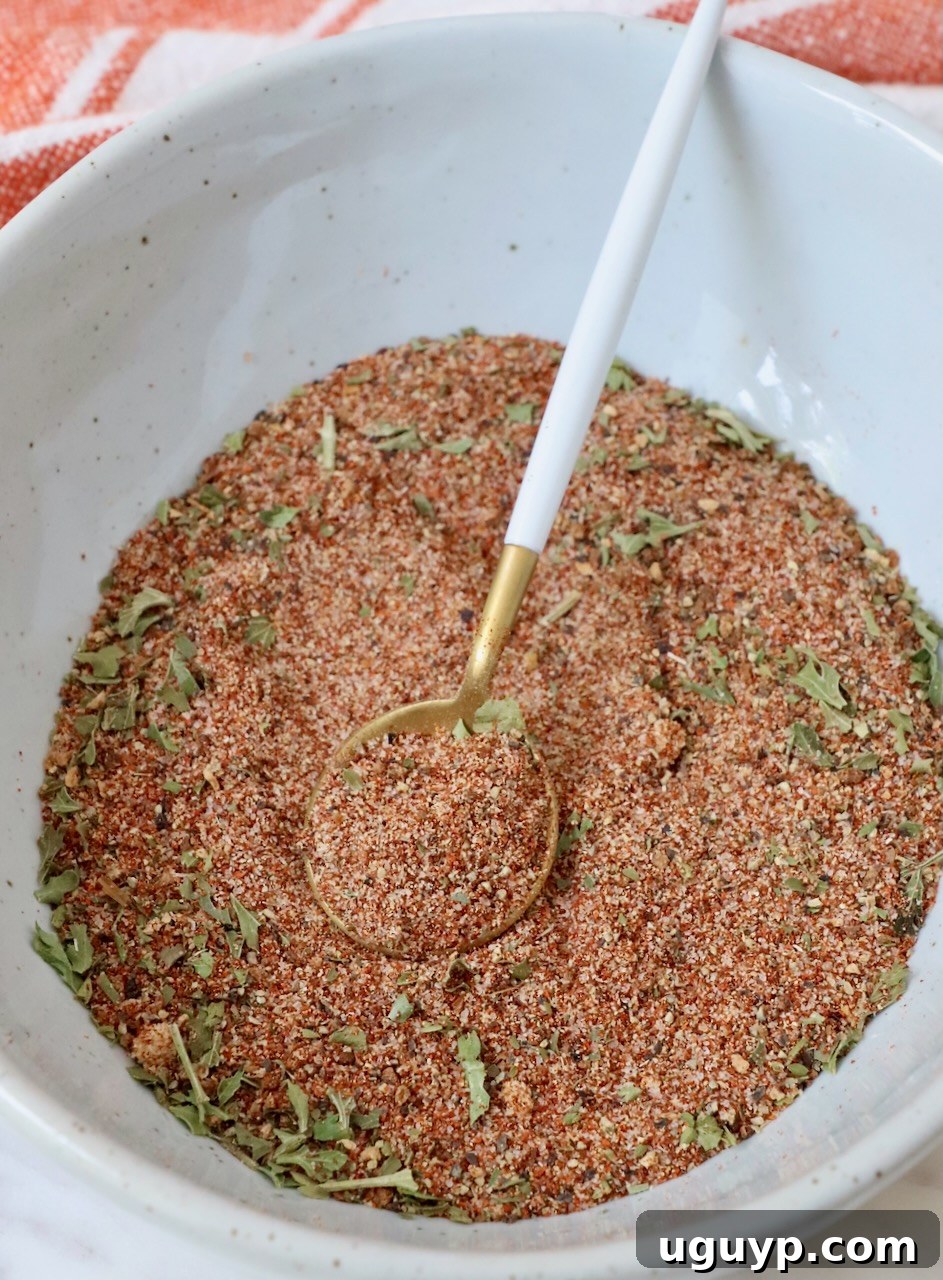 A small white bowl filled with the vibrant salmon seasoning blend, accompanied by a wooden spoon for serving or mixing.