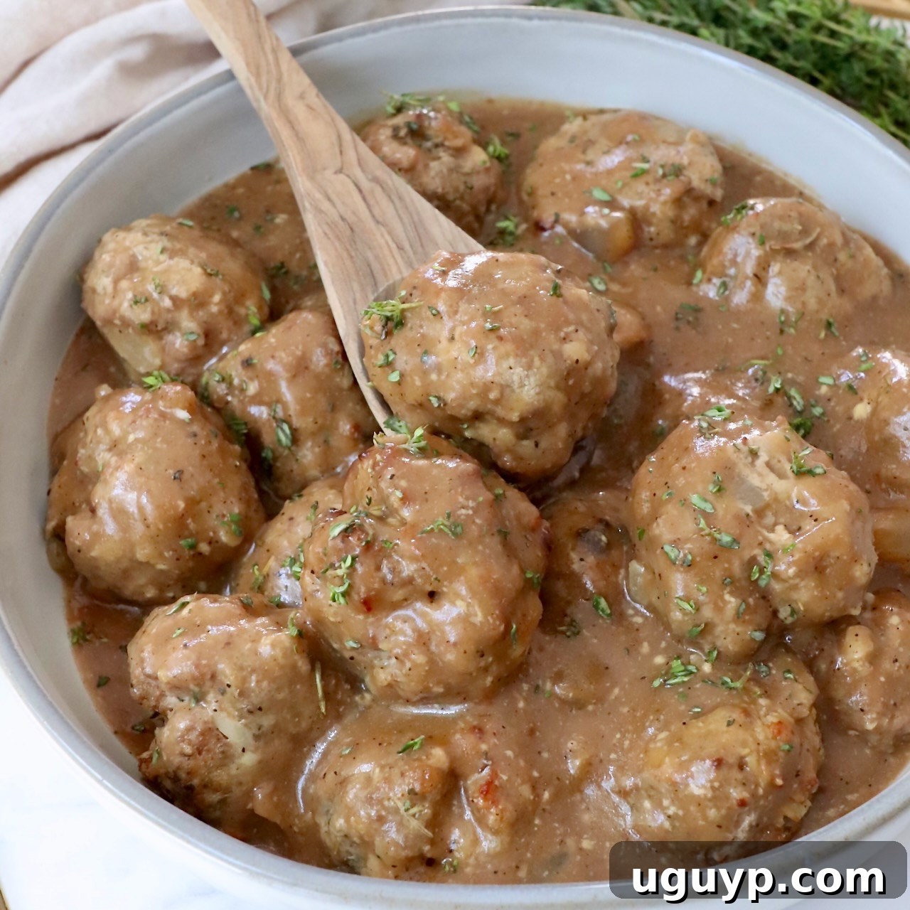 Juicy turkey meatballs generously coated in rich brown gravy, served in a bowl with a spoon, ready to be enjoyed.