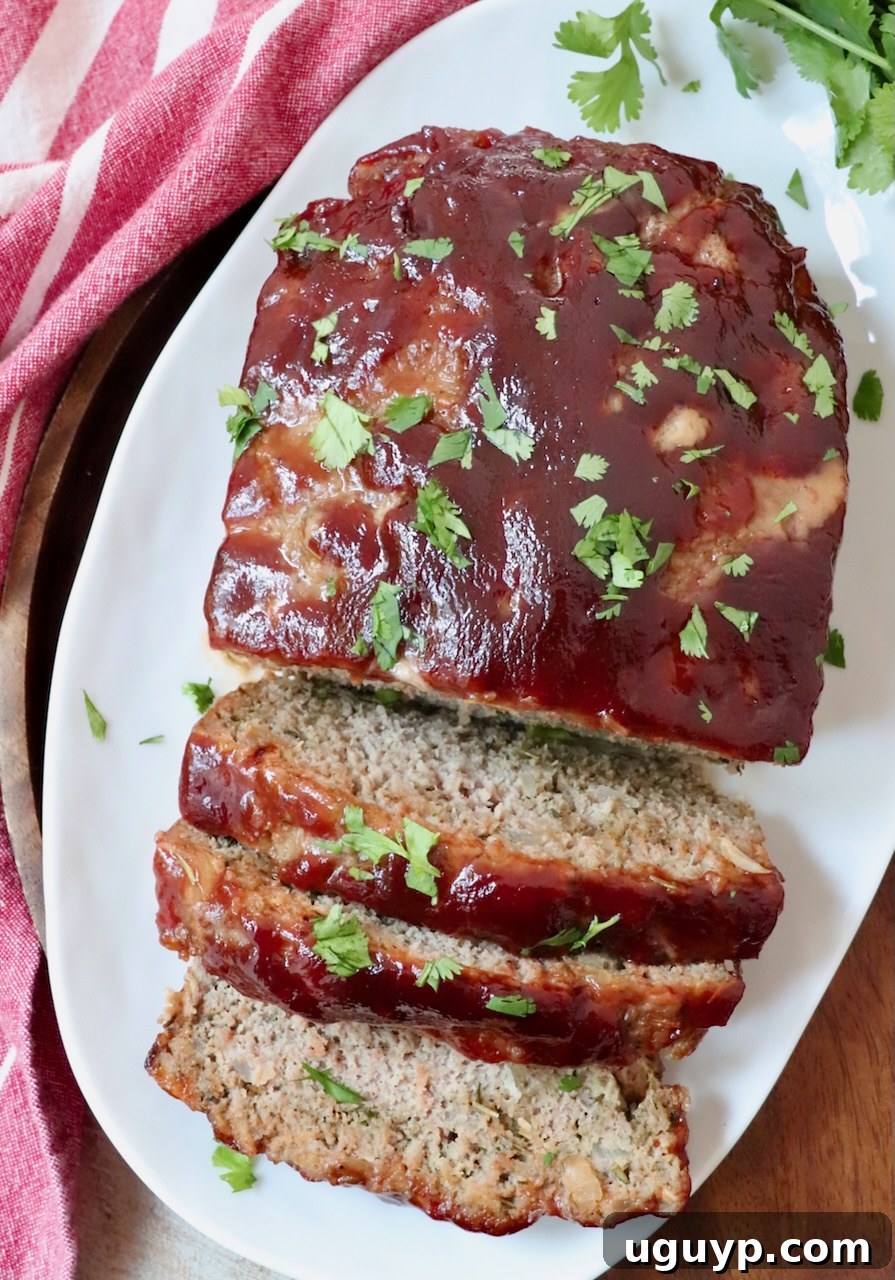 Perfectly sliced turkey meatloaf on a white plate, showcasing its moist texture and rich glaze.