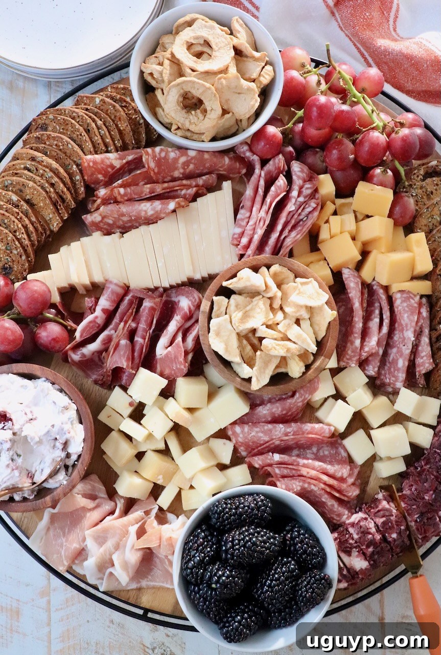 A beautifully arranged Fall Charcuterie Board featuring an assortment of cured meats, various cheeses, seasonal fruits like grapes and dried apples, and a selection of crackers.