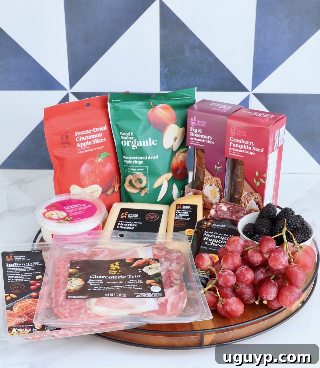 Ingredients for a Fall Charcuterie Board laid out on a round wooden serving board, ready for assembly, showcasing a variety of cheeses, meats, and dried fruits.