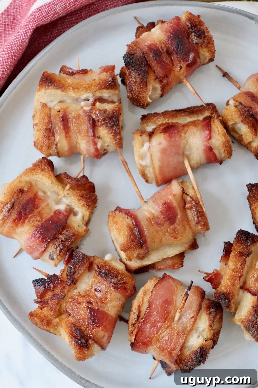 A close-up shot of several freshly baked Bacon Roll Ups on a white plate, garnished with finely chopped fresh parsley.