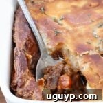 serving spoon in a beef pot pie in a baking dish