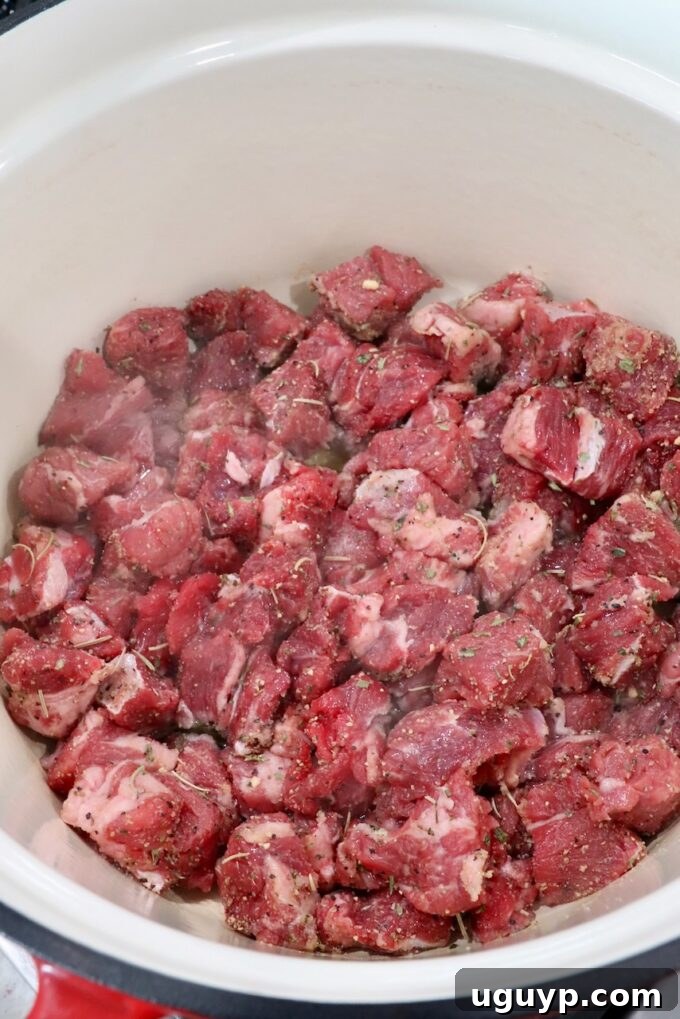 cubes of raw beef chuck roast in a cast iron dutch oven