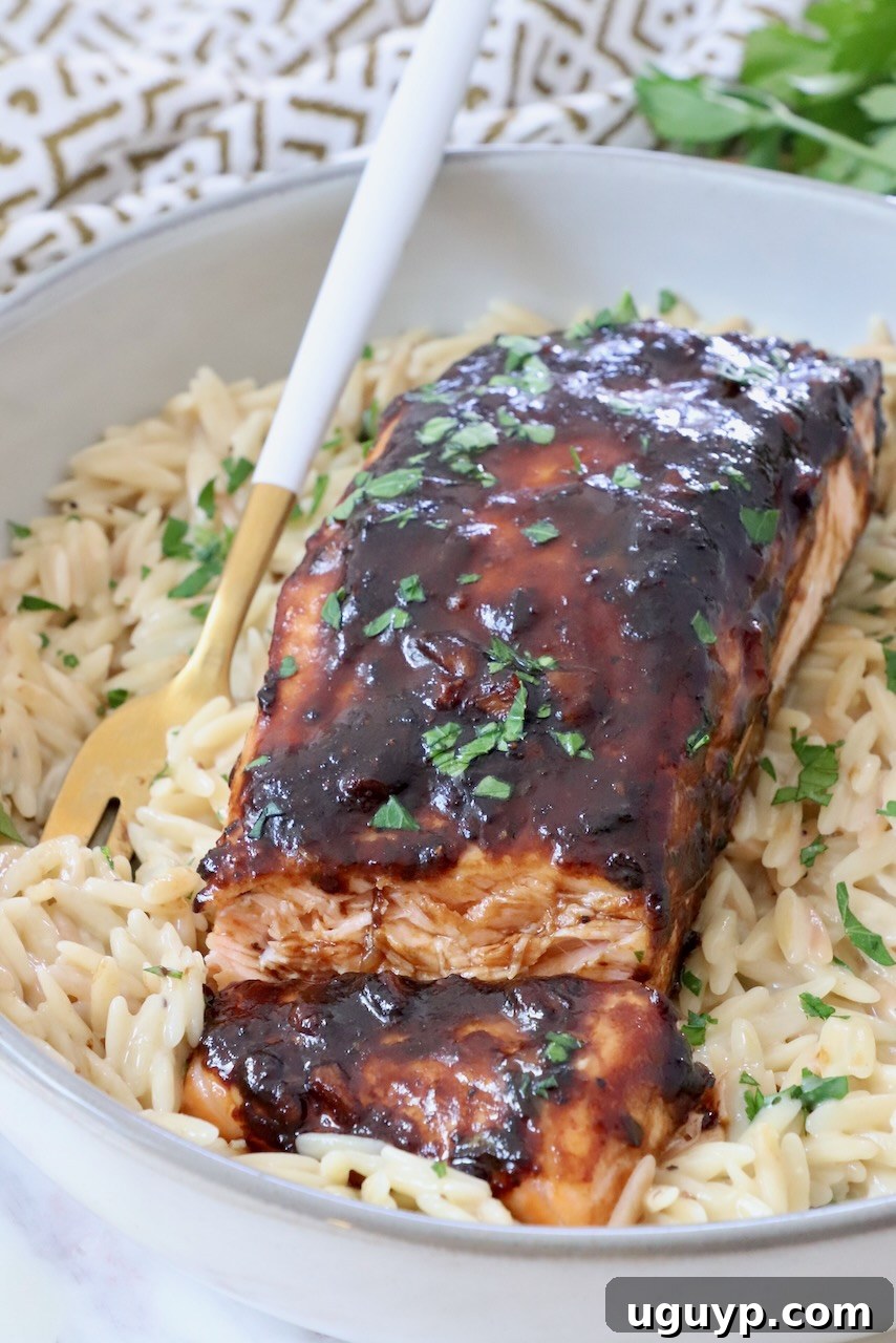 Perfectly cooked balsamic glazed salmon on a bed of orzo in a bowl with a fork, ready to be enjoyed.