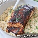 balsamic glazed salmon in a bowl with cooked orzo and a fork