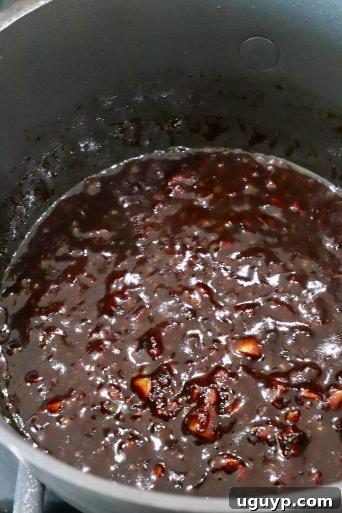 Balsamic glaze simmering in a small pot on the stove, showing its rich, reduced texture.
