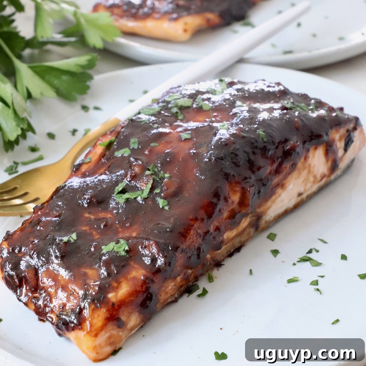 A perfectly cooked balsamic glazed salmon fillet served on a white plate with a fork, showing its flaky texture and glossy glaze.