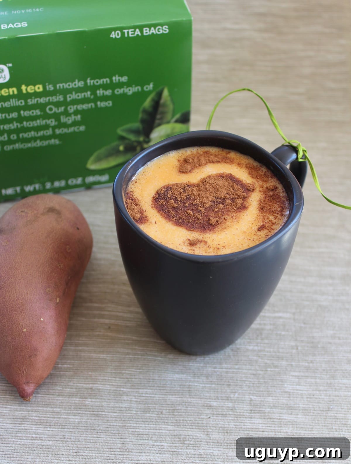 A Korean Goguma Green Tea Latte in a mug, beautifully garnished with cinnamon and pistachios, ready to be enjoyed.