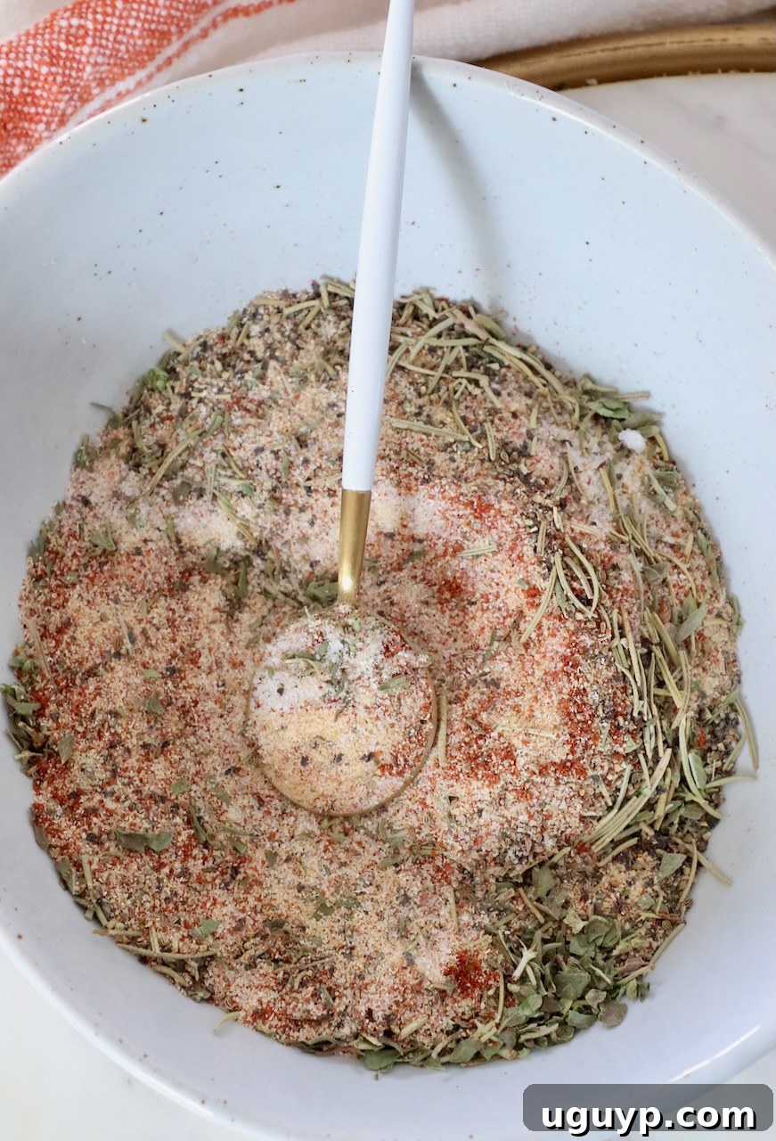 A beautiful blend of dried herbs and spices, perfectly mixed together in a bowl with a wooden spoon, showcasing the rich colors and textures of the homemade beef stew seasoning.