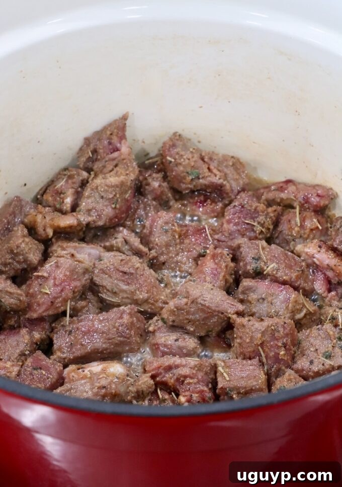 Perfectly seared, seasoned, cubed beef in a large Dutch oven, developing rich color.