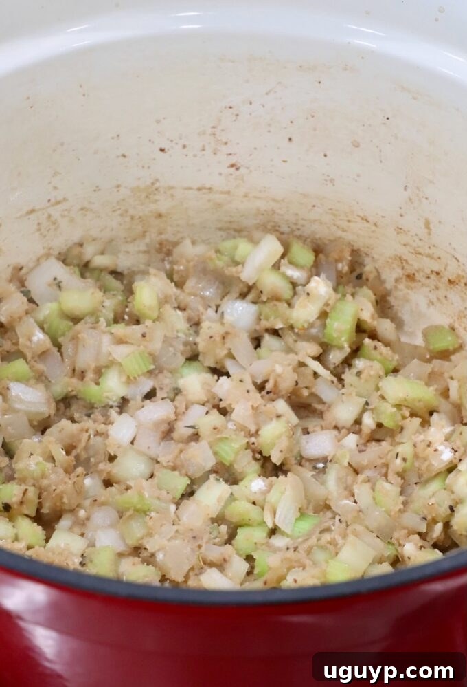 Diced onions and celery in a Dutch oven with flour and beef broth added, beginning to thicken.