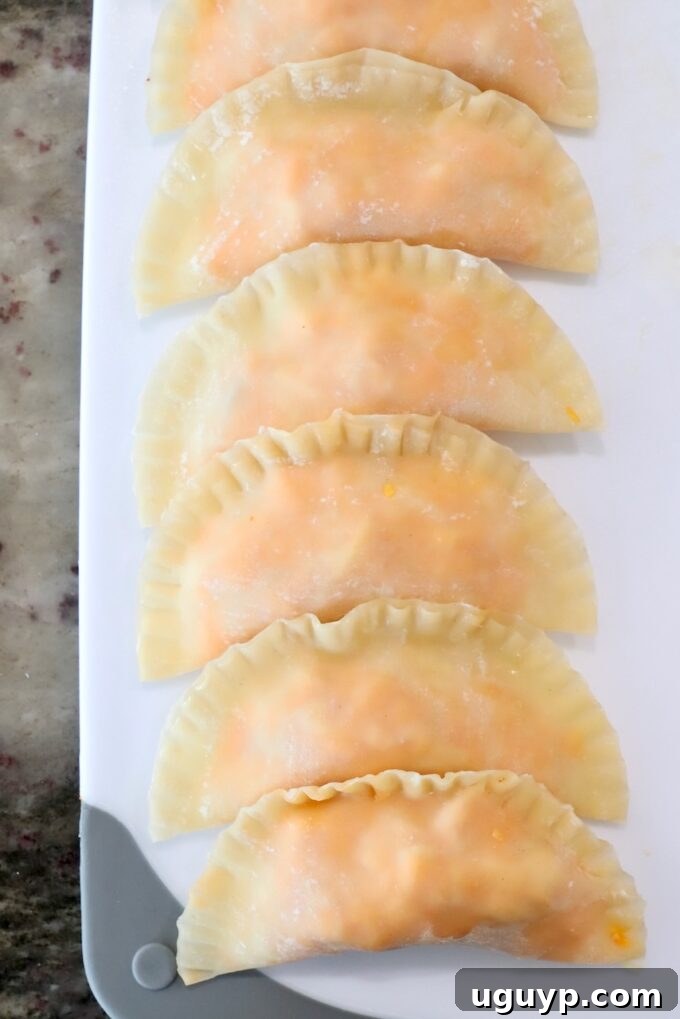 Several uncooked Buffalo chicken bites, neatly lined up on a cutting board, showcasing their consistent shape and readiness for cooking.