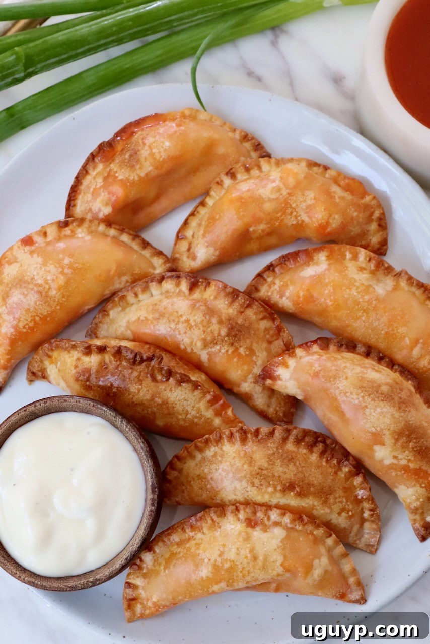A plate piled high with golden-brown Buffalo chicken bites, accompanied by a small bowl of creamy blue cheese dressing for dipping.