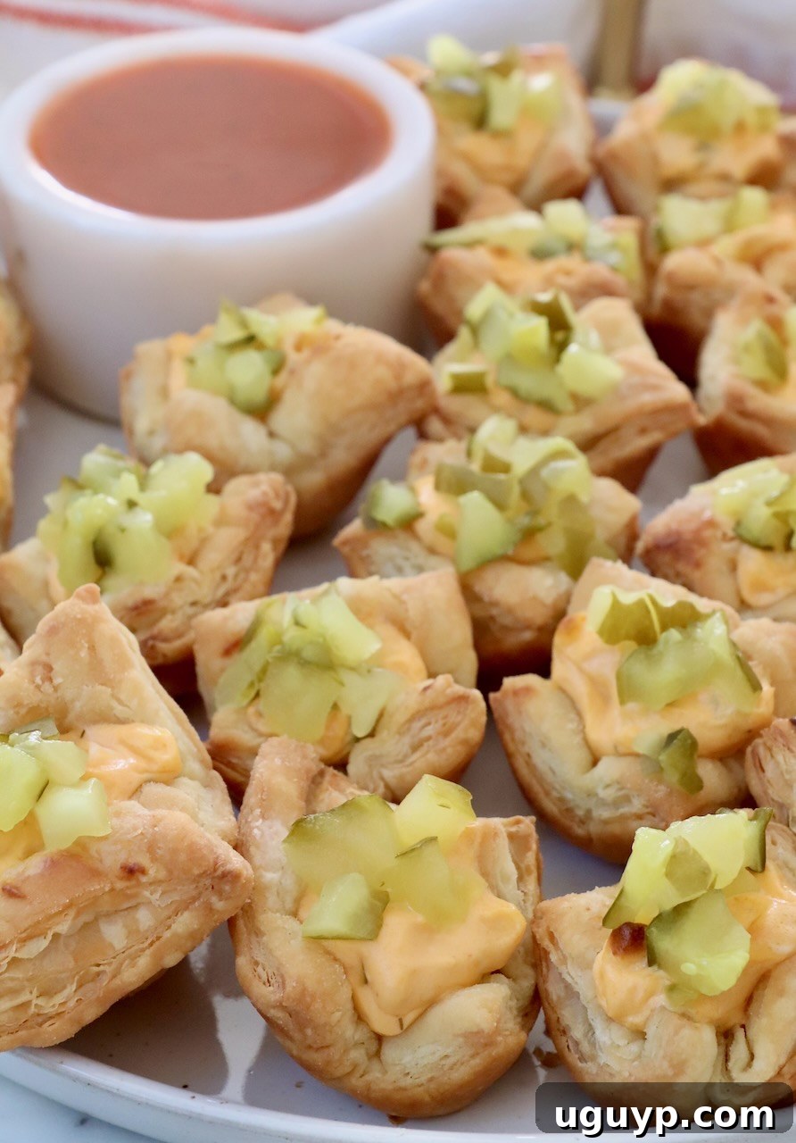 pickle puff pastry bites on a plate with a small bowl of buffalo sauce
