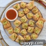 puff pastry pickles bites on a plate with a small bowl of hot sauce