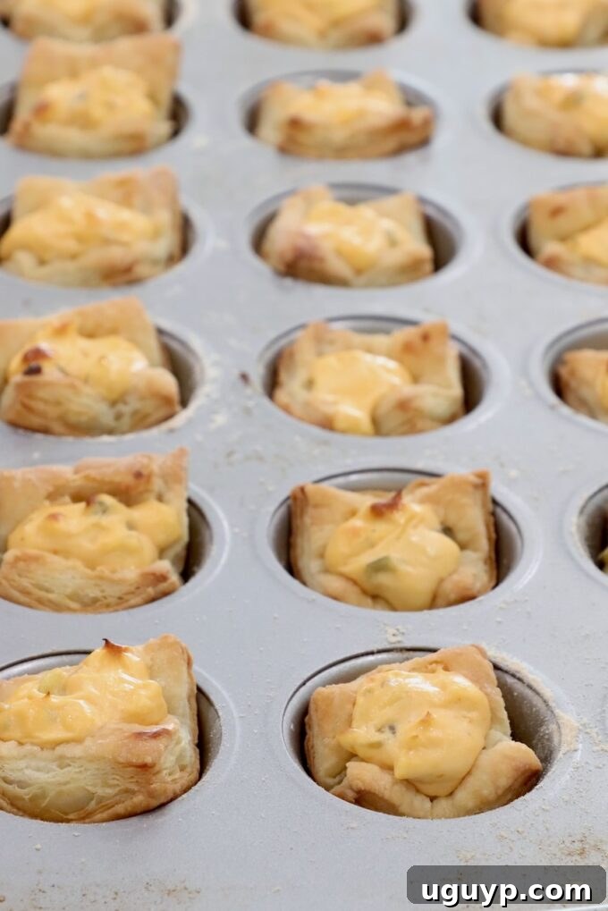 baked puff pastry dough in a mini muffin tin filled with a cream cheese filling
