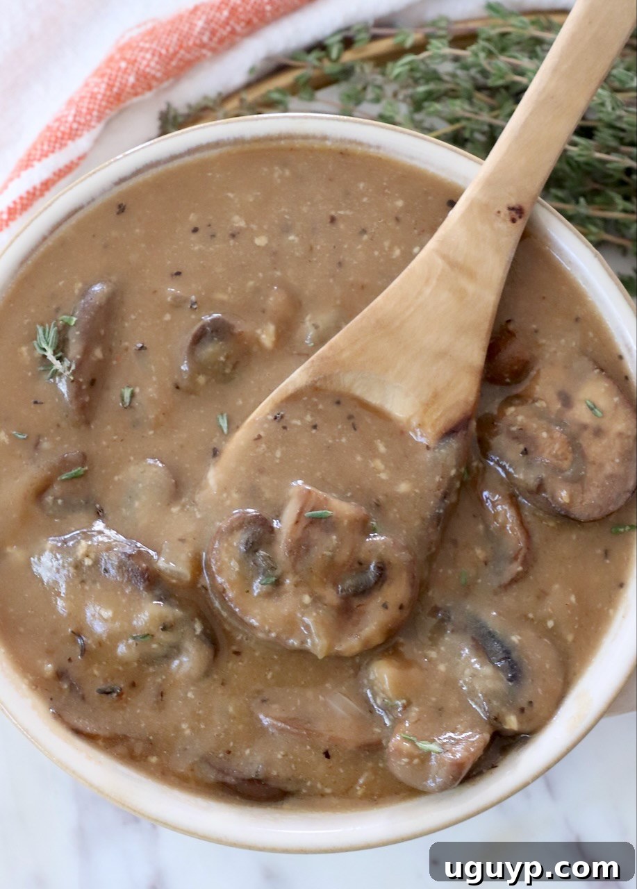 A generous serving of creamy mushroom gravy in a bowl, with a spoon ready for tasting.