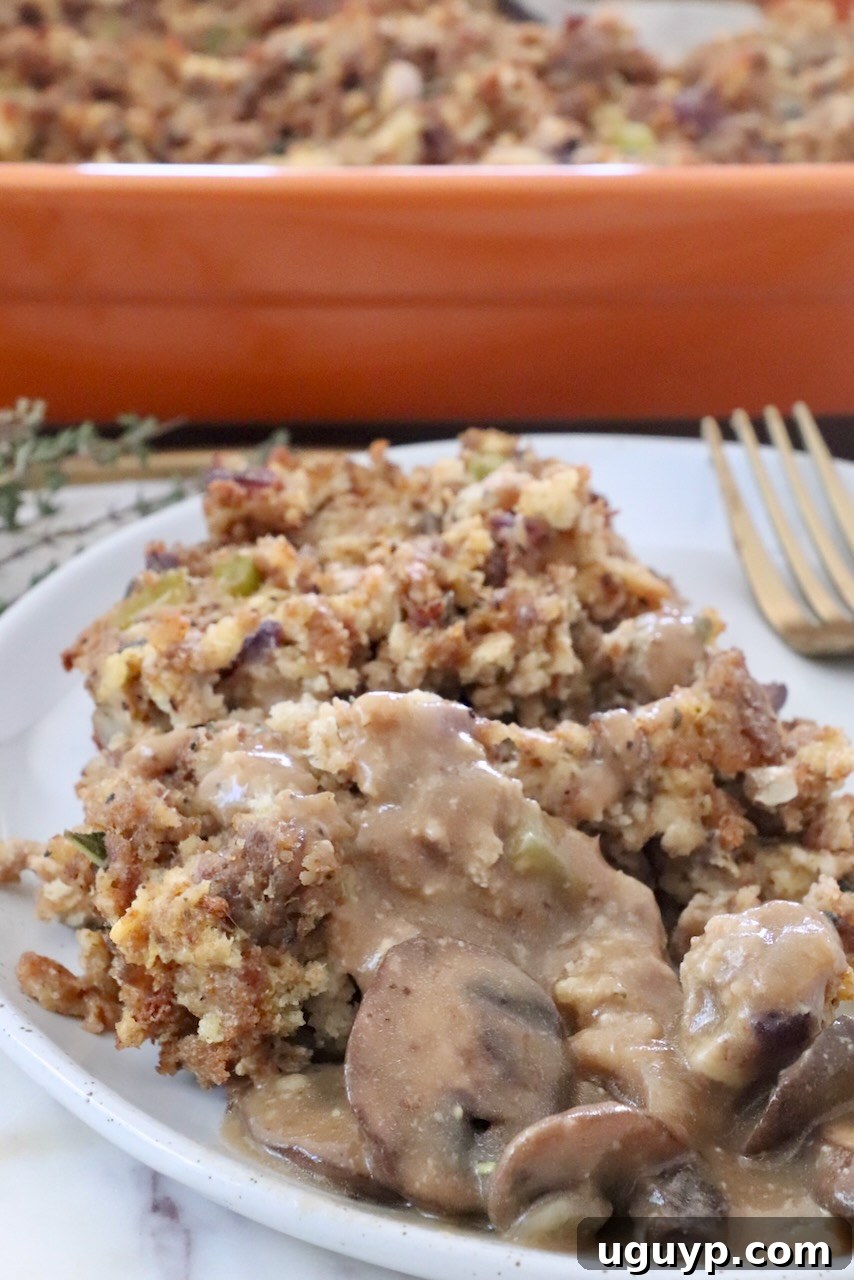 Sausage stuffing piled on a plate, generously topped with homemade mushroom gravy, ready for a comforting meal.