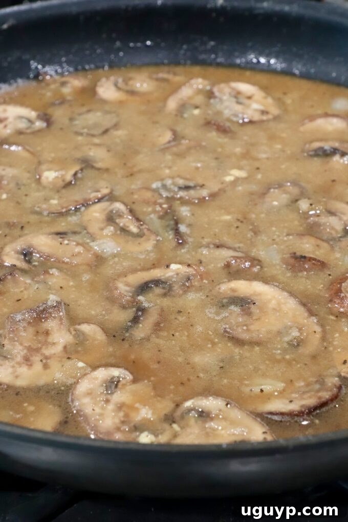 Rich and creamy mushroom gravy simmering to perfection in a large skillet, ready to serve.