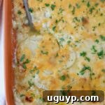 Au gratin potatoes in a casserole dish with a serving spoon, golden and bubbly.
