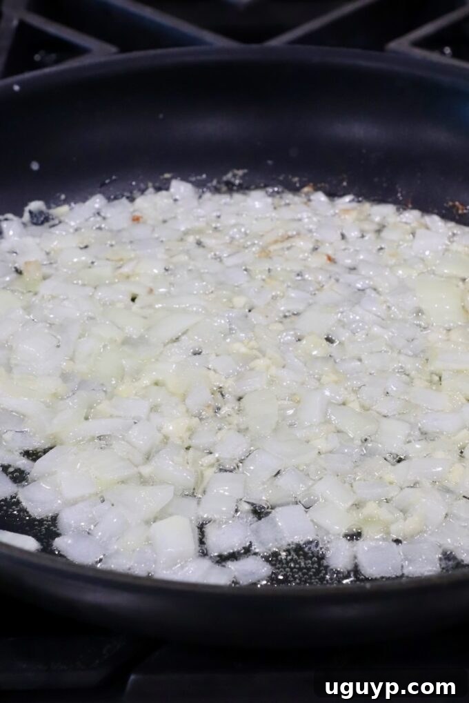 Finely diced onions and minced garlic sautéing in melted butter in a large skillet, releasing their fragrant aromas.