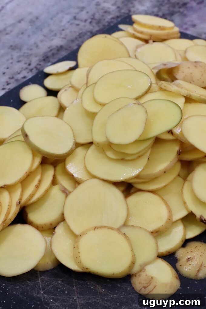 Thinly sliced Yukon gold potatoes neatly arranged on a cutting board, ready for layering.