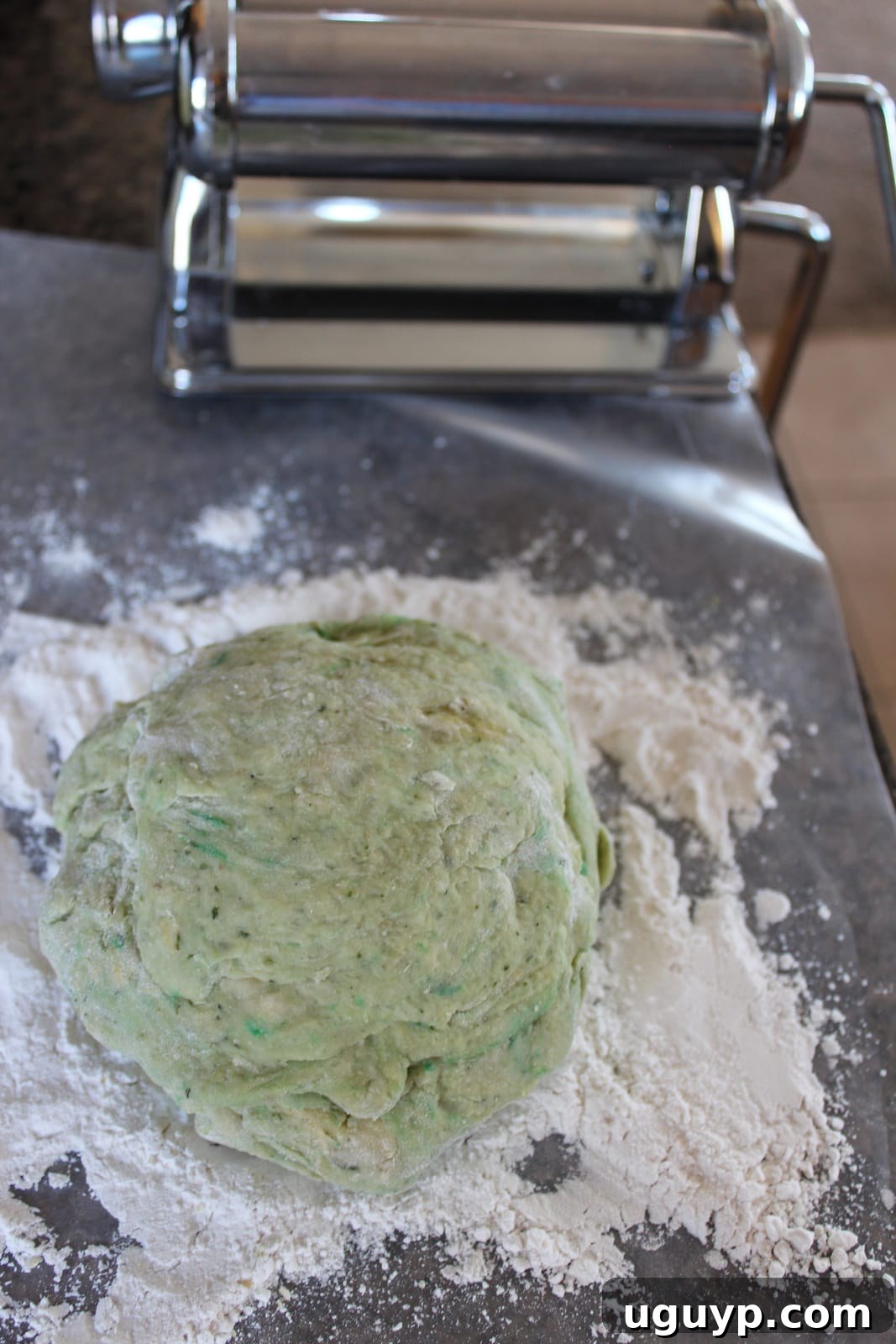 green pasta dough on top of flour on a cutting board