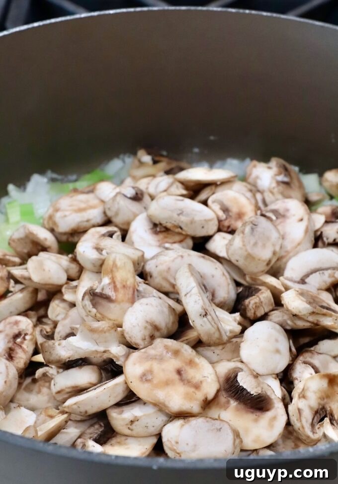 diced onions and celery with sliced mushrooms in a large pot