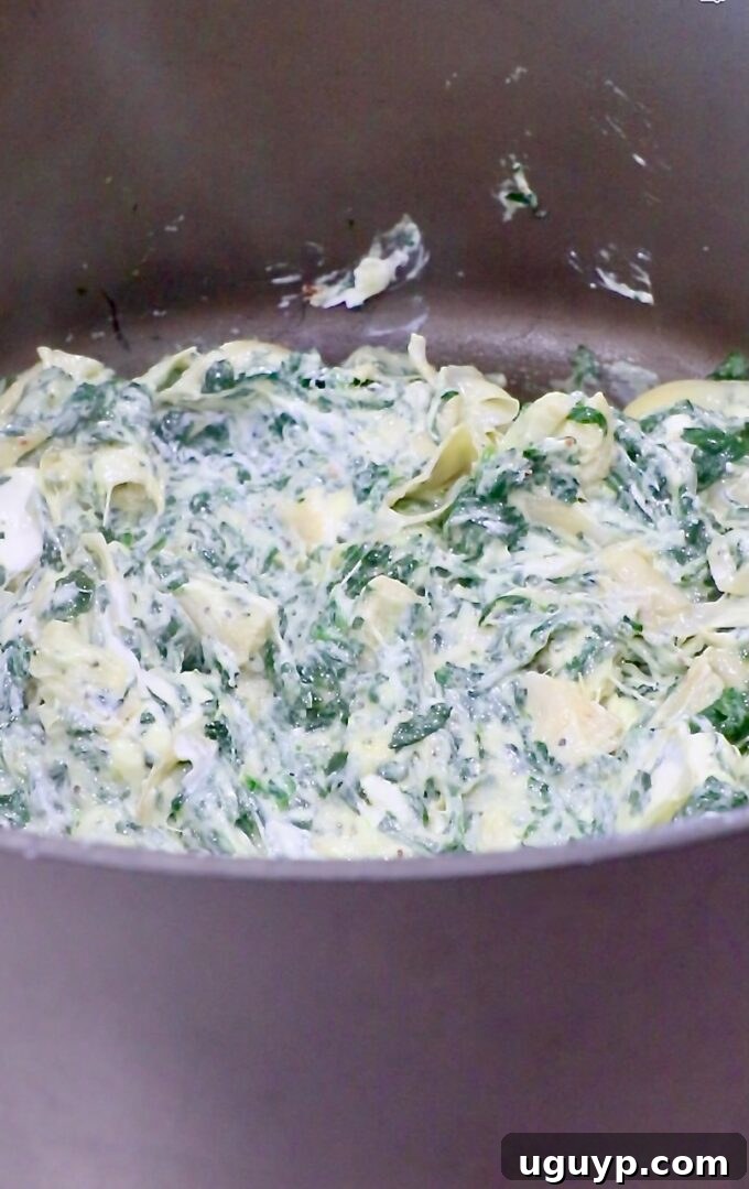 spinach artichoke dip ingredients melting together in a large pot